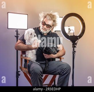 Radio host, affascinante influencer, registra uno spettacolo dal vivo con materiale e attrezzature per la fotocamera. Cani bianchi e neri. Monolocale colorato. Foto Stock