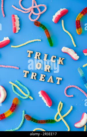 Concetto di Halloween. Decorazioni per feste di Halloween con parole TRICK O TREAT, dolci, vista dall'alto piatto su sfondo blu Foto Stock