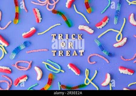 Concetto di Halloween. Decorazioni per feste di Halloween con parole TRICK O TREAT, dolci, vista dall'alto piatto su sfondo blu Foto Stock