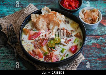 Soto Betawi è una zuppa indonesiana fatta di latte di cocco e riempita di manzo, patate e pomodori Foto Stock