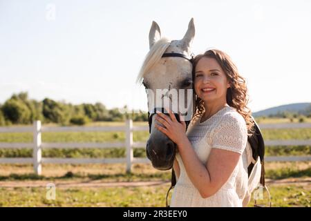 Ritratto di una giovane donna in un vestito che abbraccia il cavallo Foto Stock