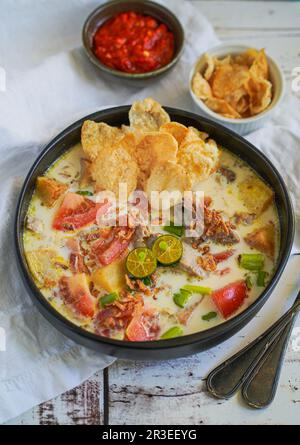 Soto Betawi è una zuppa indonesiana fatta di latte di cocco e riempita di manzo, patate e pomodori Foto Stock