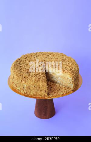 Torta di compleanno affettato sul piedistallo di legno. Bella torta di Spagna su sfondo di carta. Copia Foto Stock