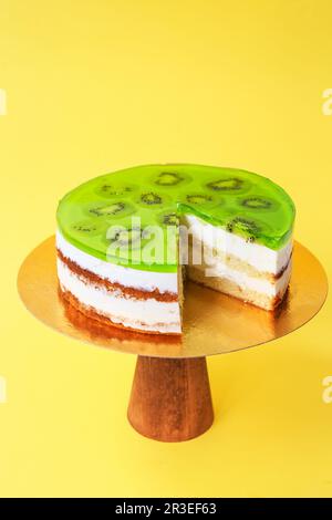 Torta di compleanno affettato sul piedistallo di legno. Bella torta di Spagna su sfondo di carta. Copia Foto Stock