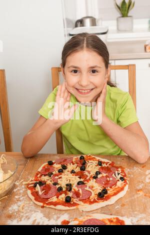 La bambina cucinò la sua pizza preferita Foto Stock