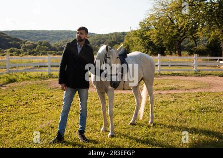 Uomo con un cavallo su uno sfondo di bella natura Foto Stock