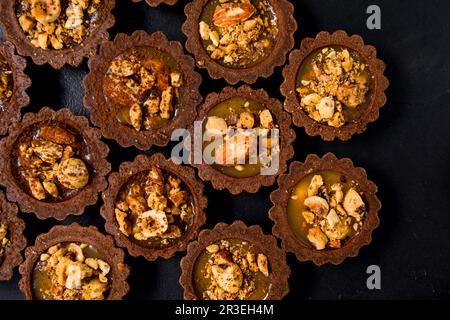 Deliziosi tartaletti di cioccolato con crema al caramello e noci Foto Stock