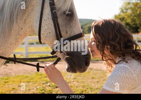 La donna con i capelli ricci si accoccolò al suo cavallo Foto Stock