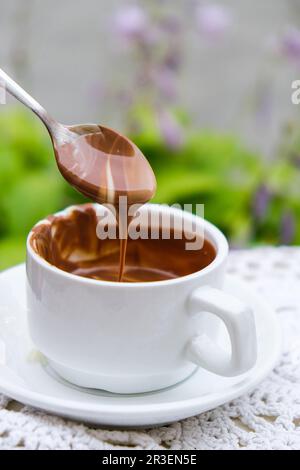 Tazza di cioccolata calda sul tavolo al bar all'aperto in estate. Caffè e colazione al ristorante. Cioccolato, latte caldo schiumato, cacao. Foto Stock