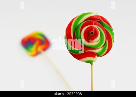 Lollipop rotondo colorato, caramella dolce brillante nei colori bianco, rosso e verde. Lollipop di Natale o Capodanno su sfondo bianco con un altro multicolore Foto Stock