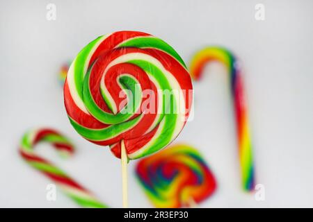 Lollipop rotondo colorato, caramella dolce brillante nei colori bianco, rosso e verde. Lollipop di Natale o Capodanno su sfondo bianco con altri multicolore Foto Stock