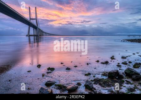 Il ponte Vasco da Gama attraversa il fiume Tago a Lisbona, Portogallo, all'alba Foto Stock