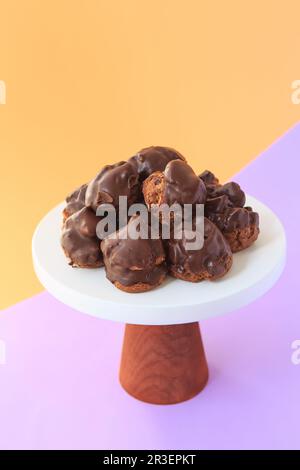 Profiteroles fatti in casa con cioccolato. Crema di boccette di cioccolato alla vaniglia ripiena su uno sfondo luminoso. Profiteroles con cre Foto Stock