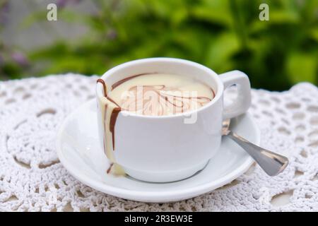 Tazza di cioccolata calda sul tavolo al bar all'aperto in estate. Caffè e colazione al ristorante. Cioccolato, latte caldo schiumato, cacao. Foto Stock