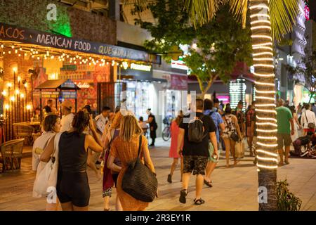 PLAYA DEL CARMEN, Messico - Febbraio 2023: La vibrante 5th Avenue si anima di notte come una moltitudine di persone riempire le strade, bagnata dal colorato glo Foto Stock