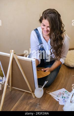 Pittore creativo in lavorazione. Artista luogo di lavoro, hobby, attrezzi artigianali. Artista femmina pittura tela. Giovane professionista wom Foto Stock