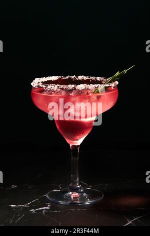 Cocktail di rosmarino alcolico o non alcolico come margarita, cosmopolita o simile su un tavolo di marmo scuro Foto Stock