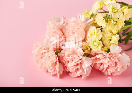 Bouquet di garofani rosa e mattiola gialla. Design concetto di saluto per le vacanze con bouquet di garofano sul dorso rosa del tavolo Foto Stock