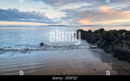 Splendido paesaggio marino al tramonto con rocce e pietre sulla spiaggia sabbiosa di Salthill a Galway, Irlanda Foto Stock