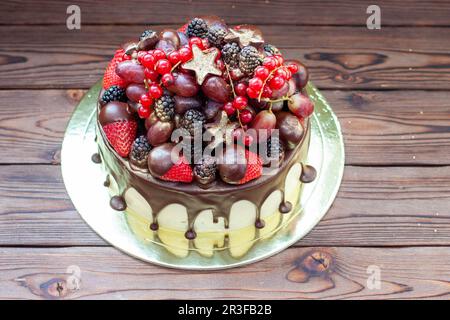 Deliziosa cheesecake con fragole fresche, lamponi, mirtillo, ribes e uva su sfondo legno, spazio libero per il testo. Foto Stock