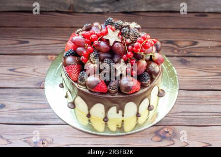 Deliziosa cheesecake con fragole fresche, lamponi, mirtillo, ribes e uva su sfondo legno, spazio libero per il testo. Foto Stock