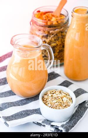 Stagionale di zucca carota frullato bevanda detox con eco metallo bere paglia vaso di vetro granola muesli farina d'avena colazione. Arancione SM Foto Stock