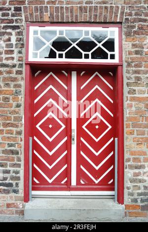 Vecchia porta di legno rosso in casa di mattoni Foto Stock