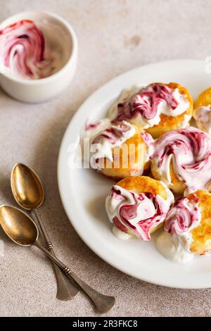 Frittelle caserette, sciroppi, frittelle di ricotta su piatto di ceramica bianca con panna acida e marmellata. Mattina sana e deliziosa Foto Stock