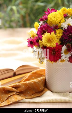 Vaso con bel bouquet, libro aperto e stoffa su tavolo di legno Foto Stock