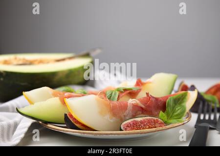 Gustosi meloni, jamon e fichi serviti su un tavolo bianco Foto Stock