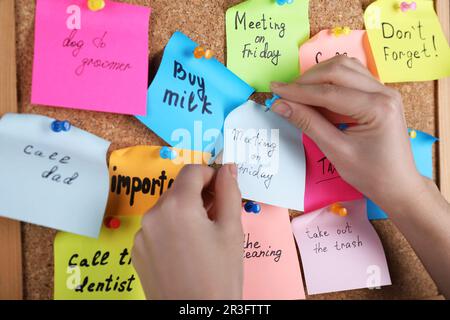 Donna pinning carta nota con frase riunione il Venerdì a sughero bordo, primo piano Foto Stock