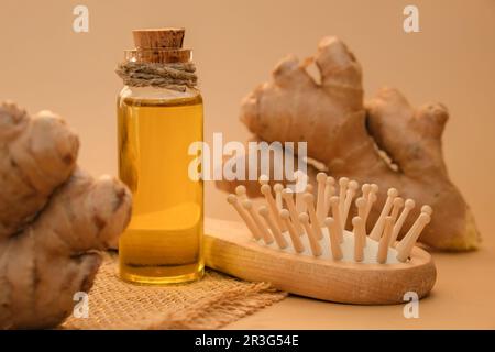 Bottiglia di vetro di olio essenziale di zenzero, radice di zenzero su fondo beige. Vita alternativa sana. Ingredienti cosmetici naturali Foto Stock