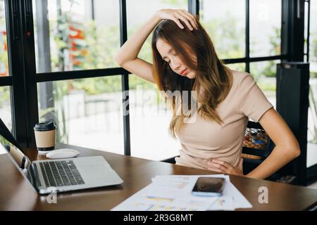 Donna d'affari freelance che soffre di dolore al collo causato da un uso prolungato del notebook Foto Stock