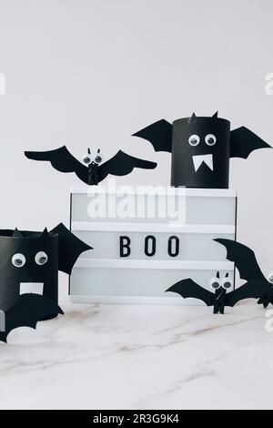 Scatola luminosa con testo BOO intorno ai pipistrelli di carta. Decorazione per feste di Halloween. Biglietto d'auguri per le vacanze autunnali Foto Stock