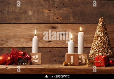 Terzo Avvento, tre candele che bruciano su un rustico tavolo di legno con decorazione di Natale Foto Stock