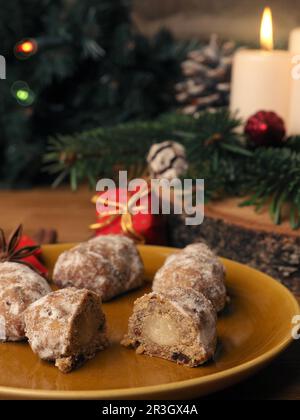 Delizioso stollen di Natale su un piatto di ceramica di fronte a una corona di Avvento e decorazioni natalizie, cibo di stagione Foto Stock