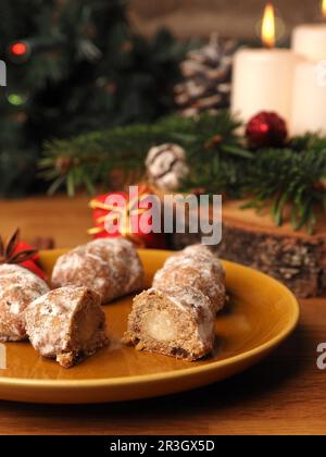 Delizioso stollen di Natale su un piatto di ceramica di fronte a una corona di Avvento e decorazioni natalizie, cibo di stagione Foto Stock