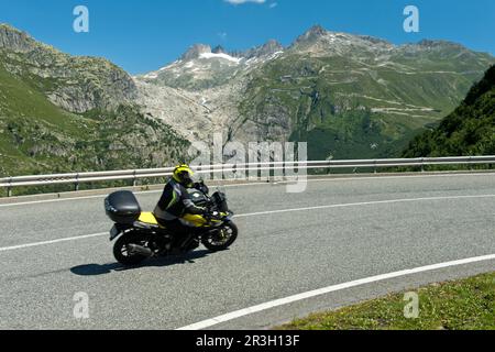 Moto in salita al Passo Furka, dietro il letto ghiacciato del ghiacciaio del Rodano, strada Furkapas vicino a Gletsch, Vallese, Svizzera Foto Stock