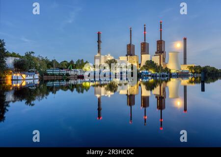 Una centrale combinata di calore ed energia elettrica a Berlino di notte con un perfetto riflesso in acqua Foto Stock