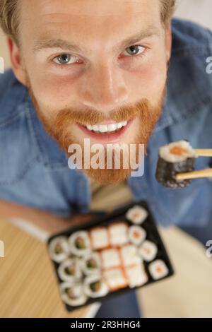 uomo in possesso di sushi con bacchette vista dall'alto Foto Stock