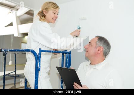 l'operaio parla con una pittrice femminile Foto Stock