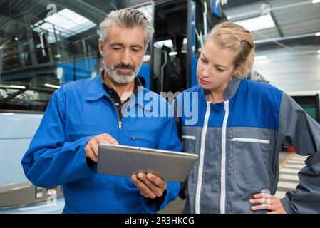 uomo e donna che usano un tablet per riparare l'auto Foto Stock