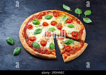 Tradizionale pizza italiana napoletana margherita con pomodori e mozzarella servita in primo piano su una vecchia tavola rustica con testo Foto Stock
