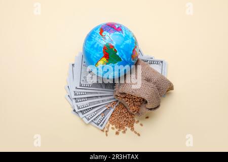 Concetto di importazione ed esportazione. Globo, sacchetto di grani di grano e banconote su fondo beige, piatto Foto Stock