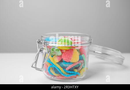 Gustose caramelle di gelatina in vaso aperto su tavolo bianco Foto Stock