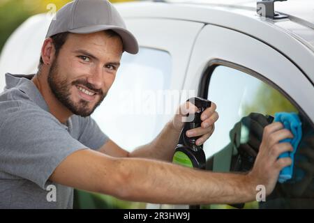 giovane uomo che pulisce la sua auto con un panno Foto Stock