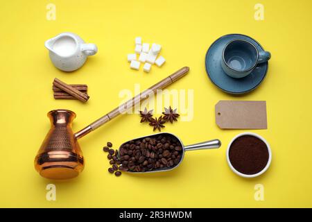 Composizione piatta con caffettiera turca e fagioli arrostiti su fondo giallo Foto Stock