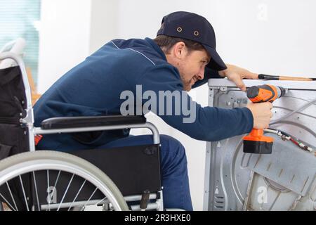 un operatore non valido ripara una lavatrice in lavanderia Foto Stock