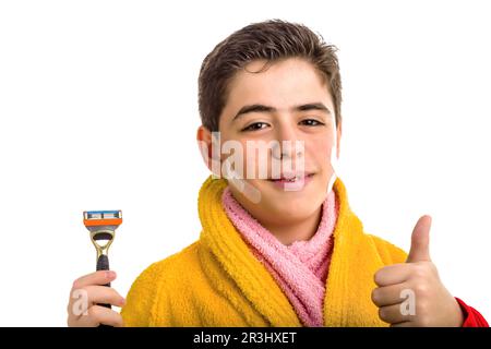 Ragazzo in accappatoio giallo e asciugamano rosa che tiene un rasoio fa segno di successo Foto Stock