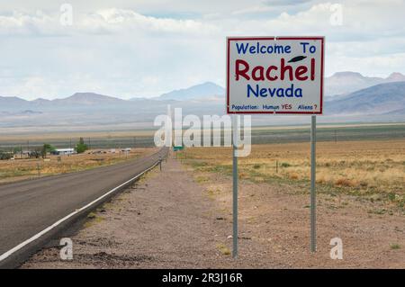 Il cartello Benvenuti a Rachel Nevada si trova accanto a una lunga strada a due corsie dritta che conduce alle lontane montagne del deserto, Extraterrestrial Highway, Nevada. Foto Stock